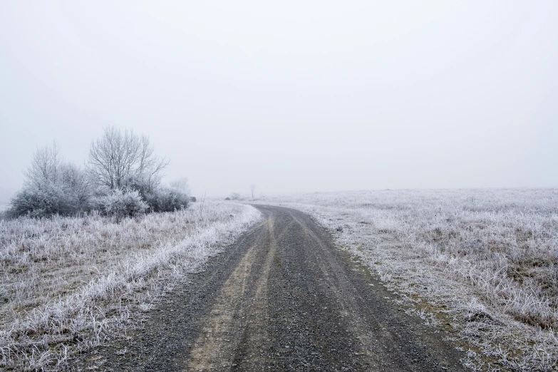 an empty road in a snowy day on the horizon