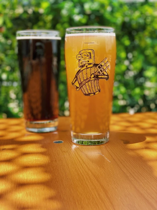 two glasses of beer sitting on top of a table