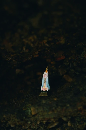 small buddha statue stands on rocks in a dark room