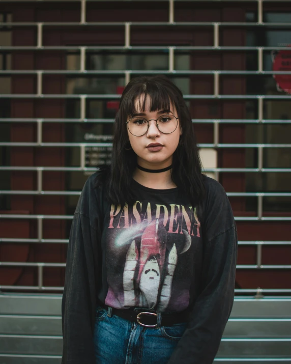 a woman wearing a black shirt stands against a building wall