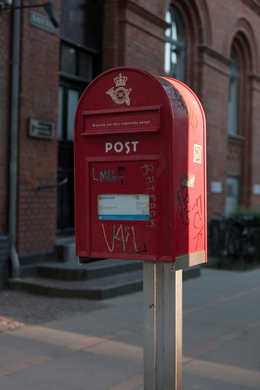 there is a red mailbox that has graffiti on it