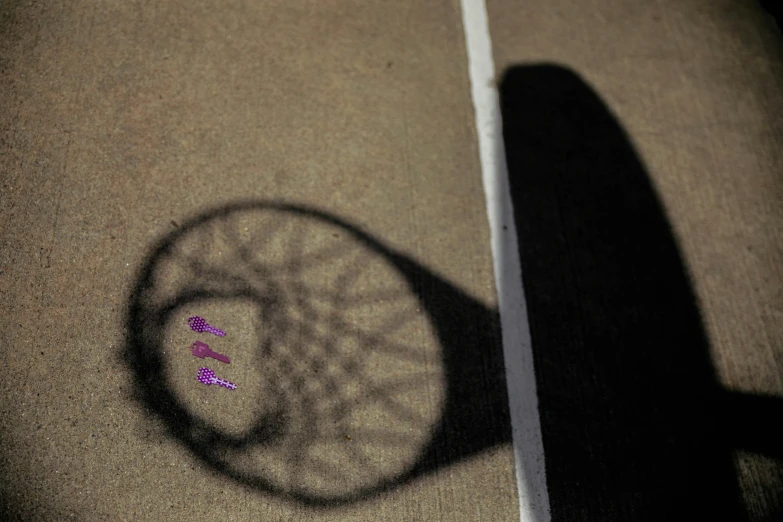 the shadow of a tennis racket with pink thread on it