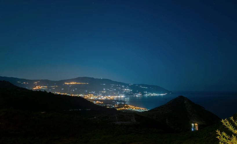 a town on the mountains under a blue sky at night