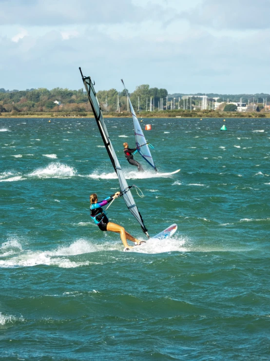 three people in the ocean wind sailing