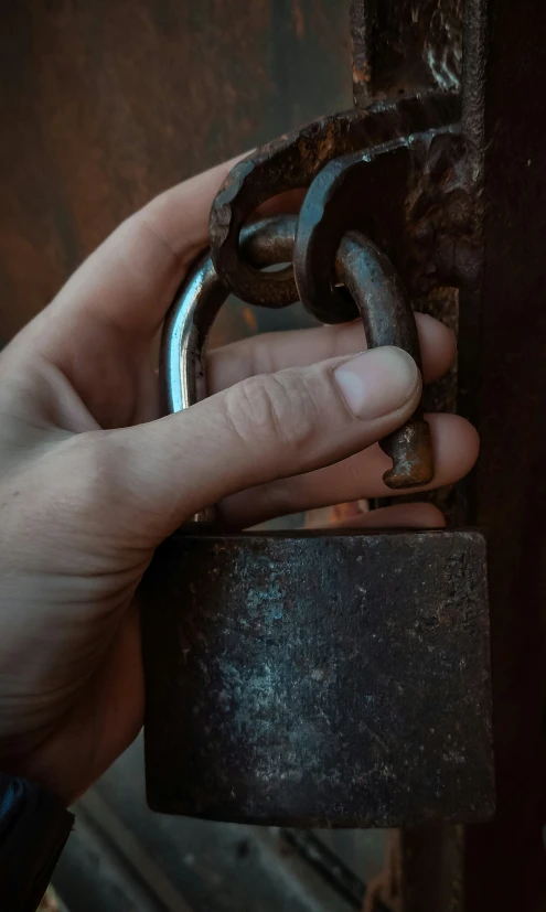 a hand holding a chain near a padlock