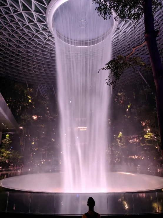 this is a big white circular fountain in the middle of a building