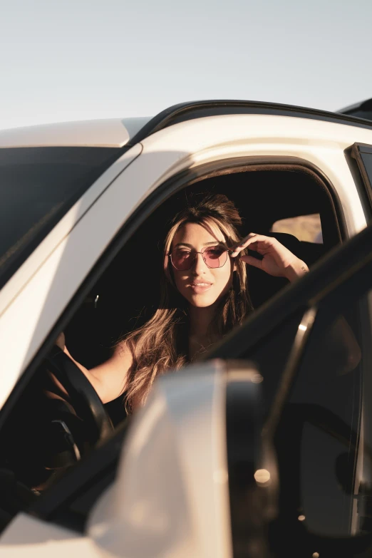 a woman wearing sunglasses is in a white car