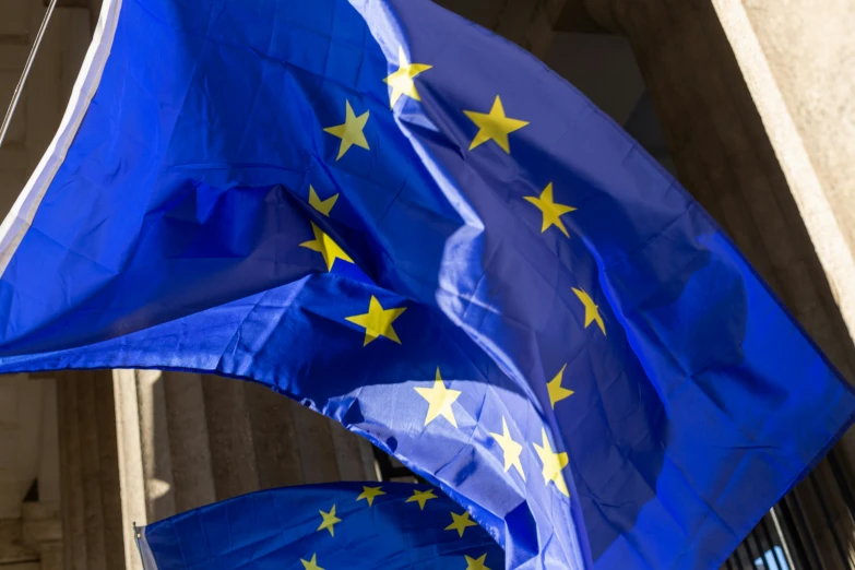 two blue flags with stars in the center, outside of a building