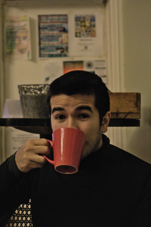 a man sitting down drinking coffee with his eyes closed