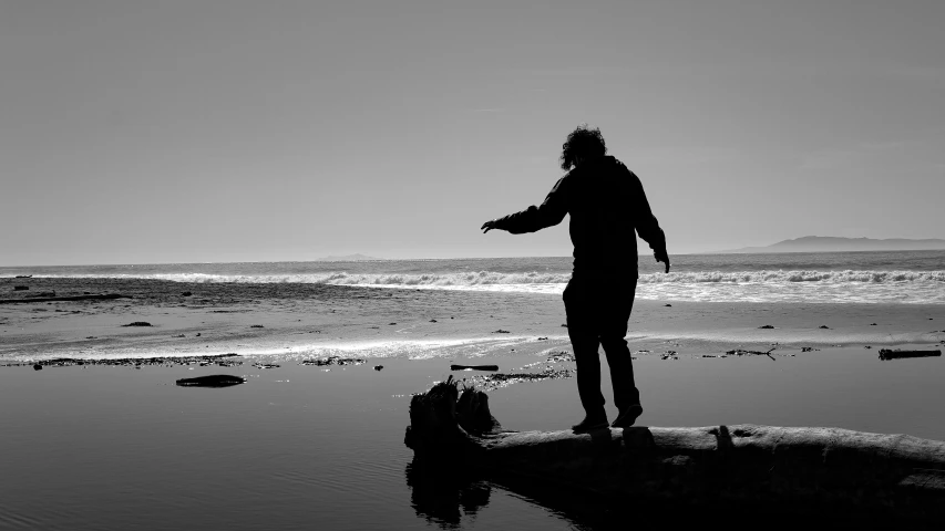 a man standing on a beach throwing a ball in the water