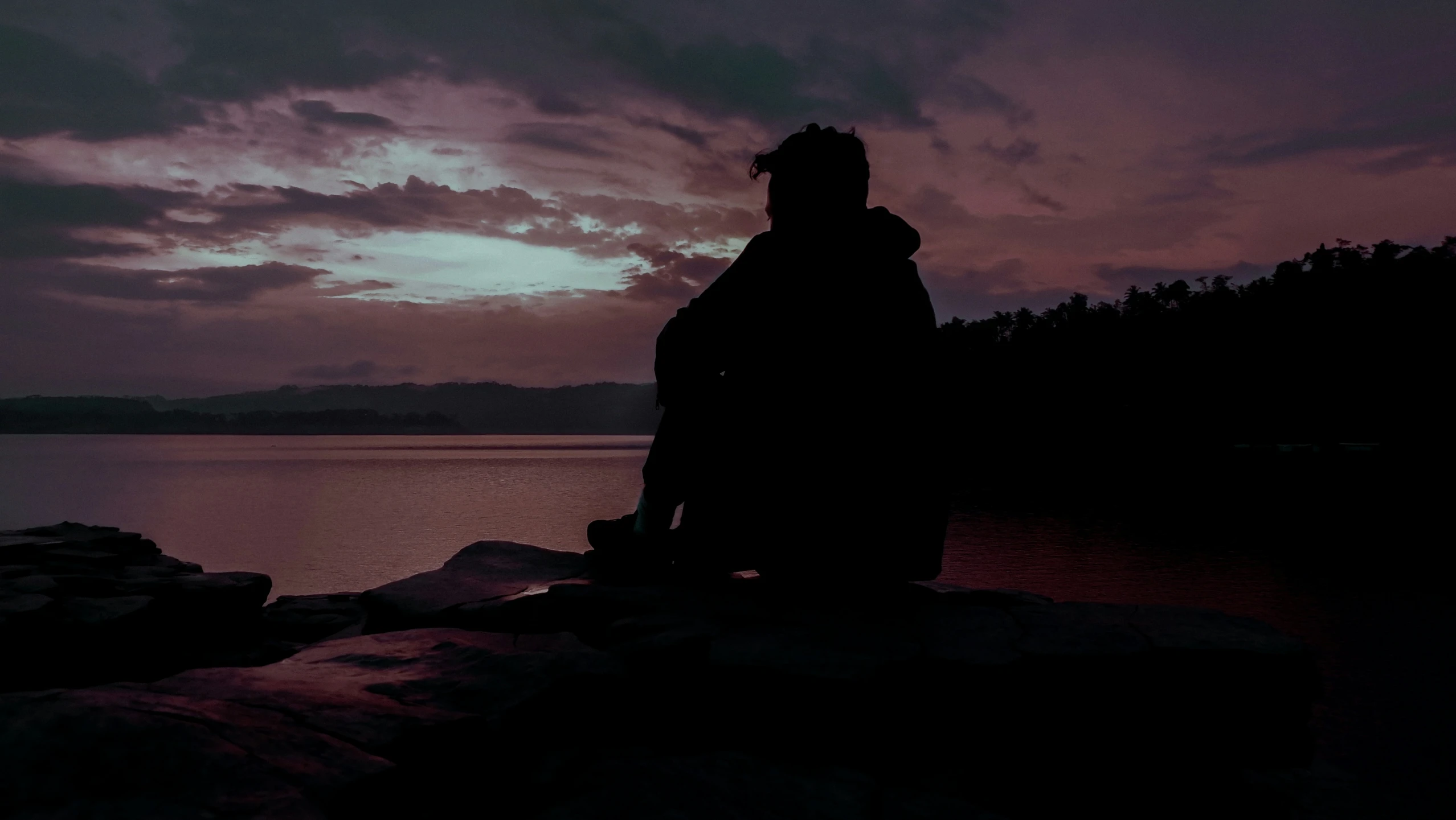 a person standing on top of a rock next to water