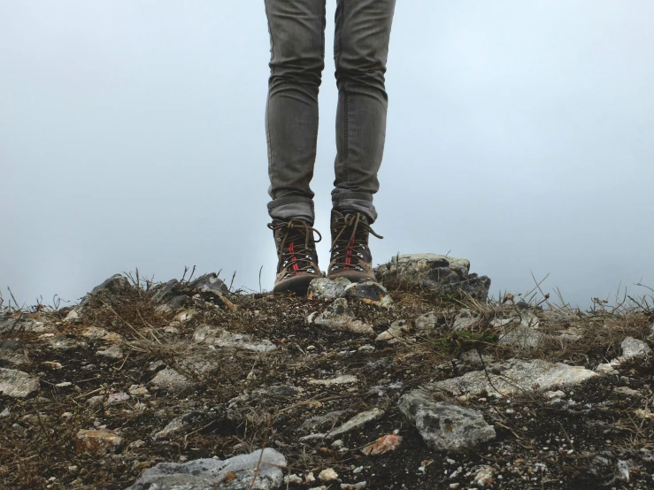 someone standing on a hill holding onto their umbrella