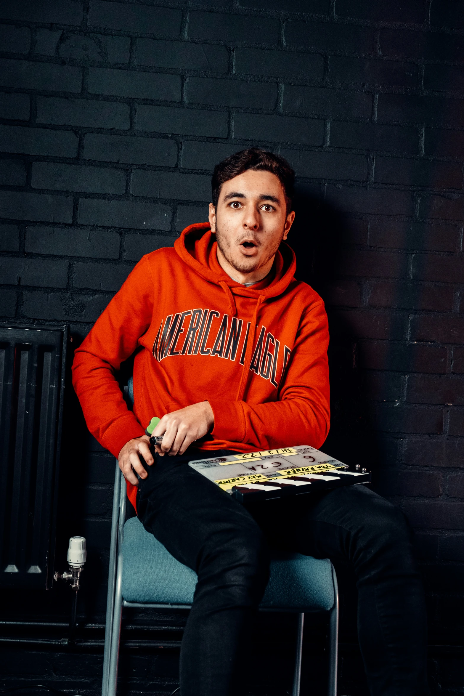 a man sitting on a chair in an orange sweatshirt