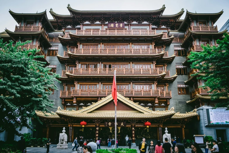 people standing outside of an oriental building with a flag