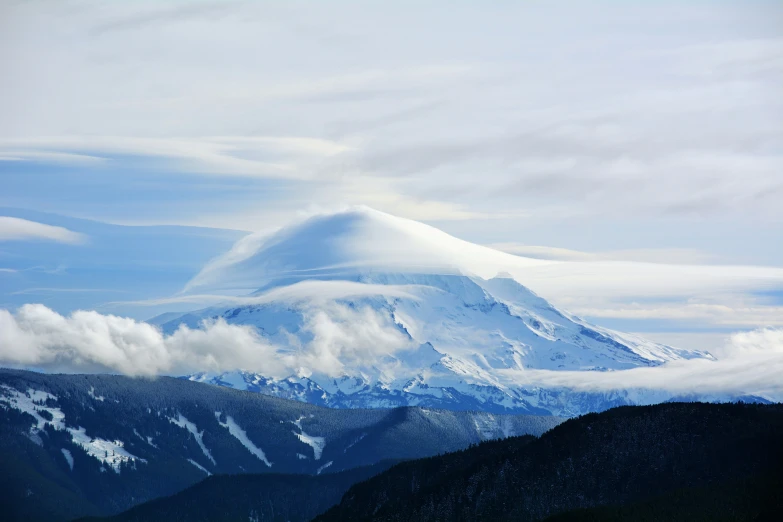 clouds forming behind a snowy mountain peak