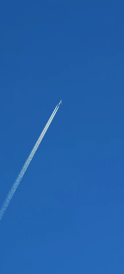 jet airliner leaving contrail flying across blue sky