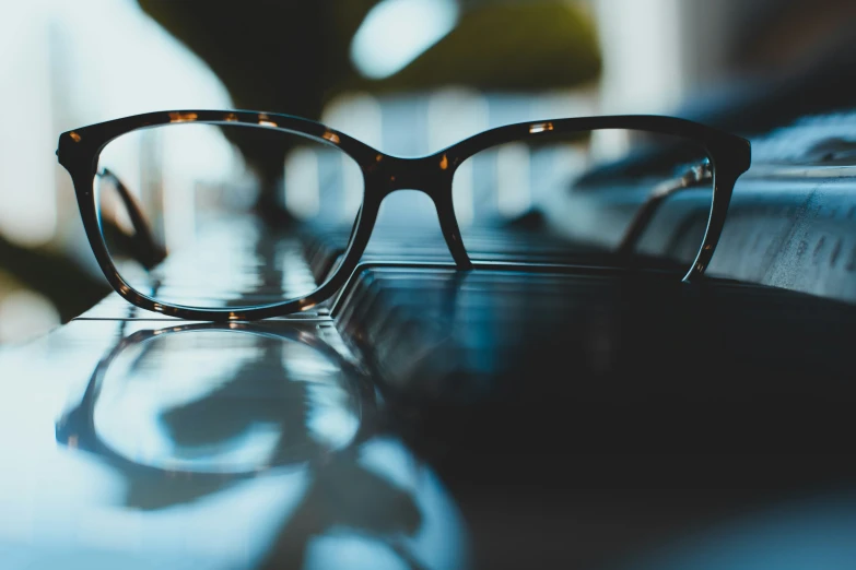 the reflection of a pair of glasses sits on a desk