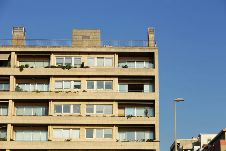 a tall beige building with balconies on top