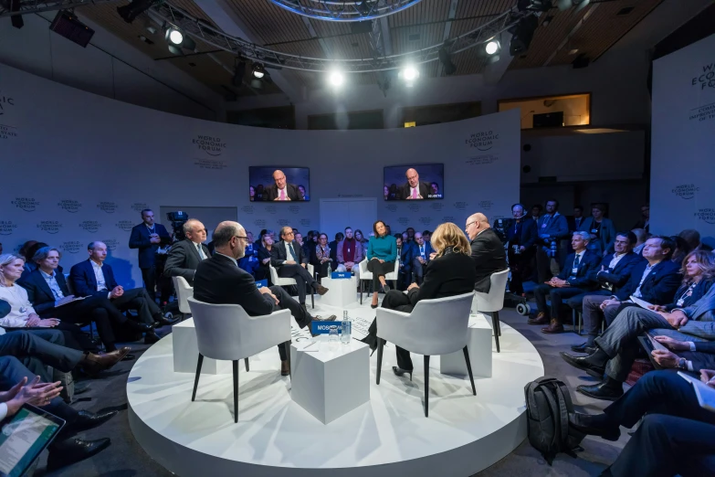 people sitting in chairs on a stage to listen