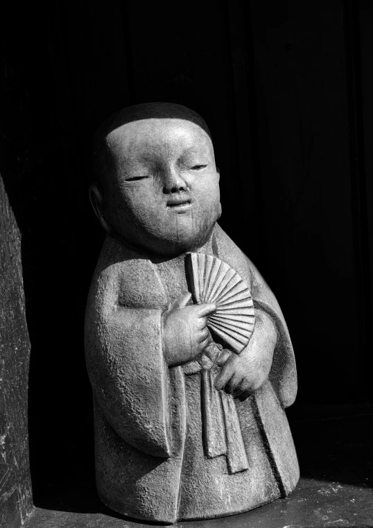 a statue of a small buddha with a fan