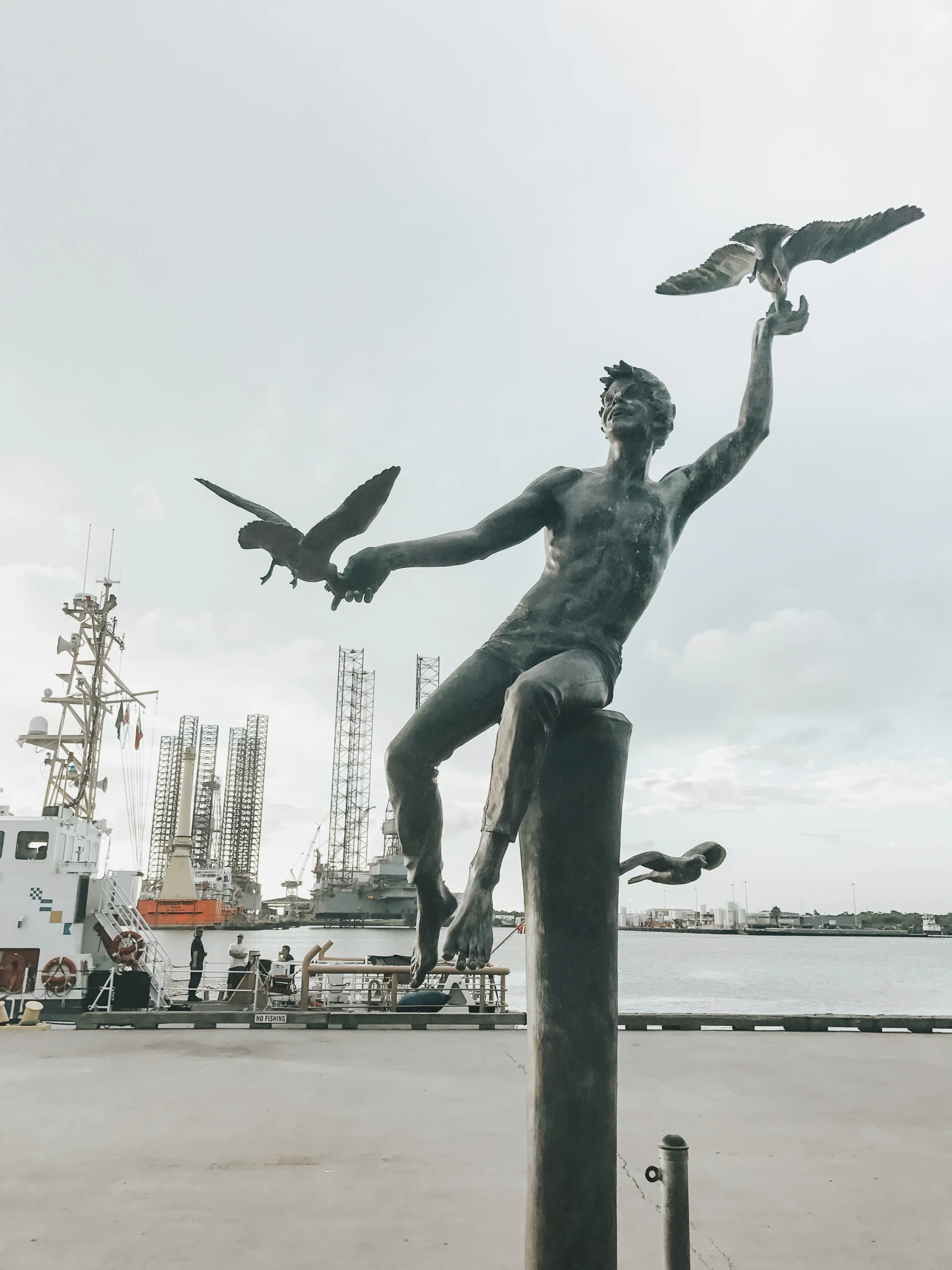 statue of a man and birds in a harbor