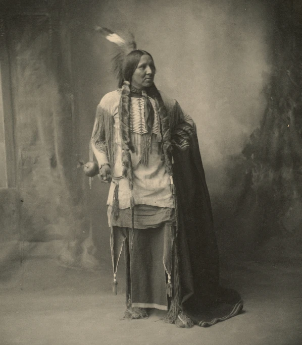 an old time native american indian standing next to a tree