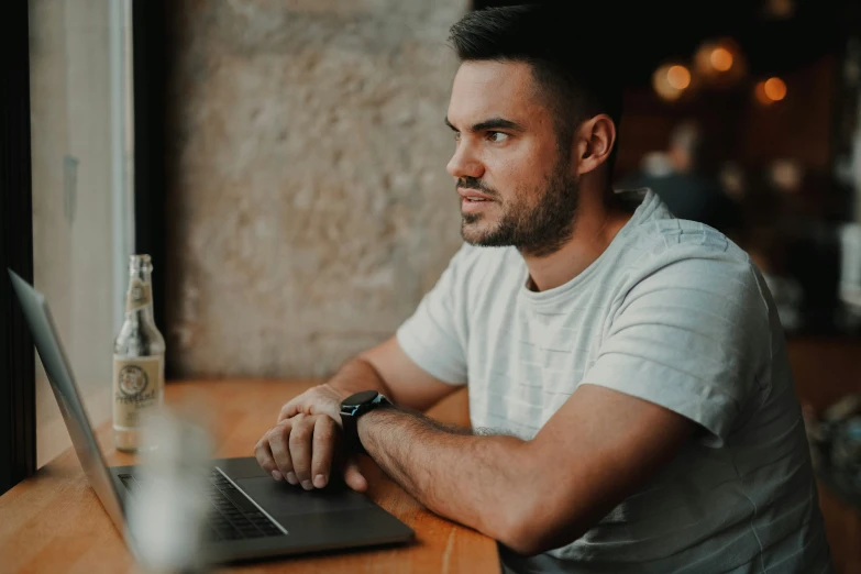 a man that is sitting at a table in front of a laptop