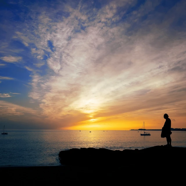 a man looks out over the water as the sun sets