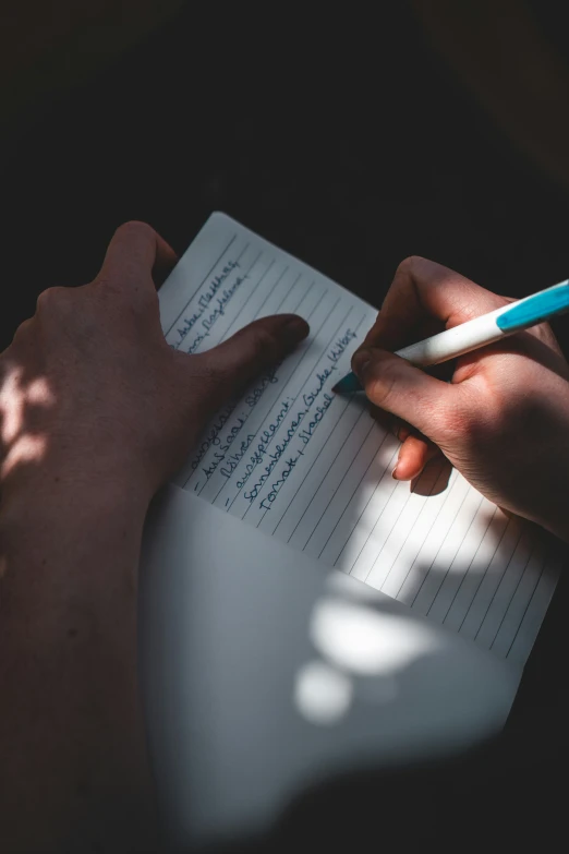 a person writing in a notebook on a desk