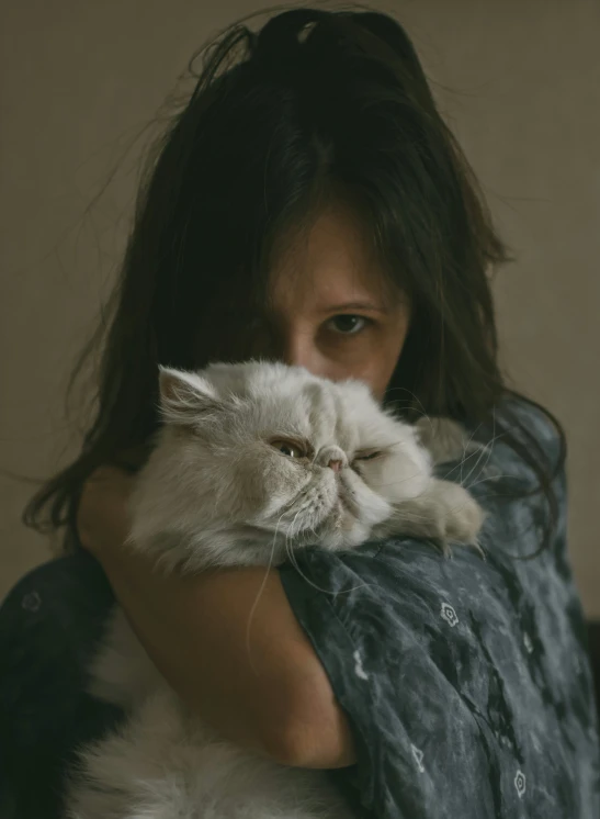 a woman holding a white cat while wearing a jacket