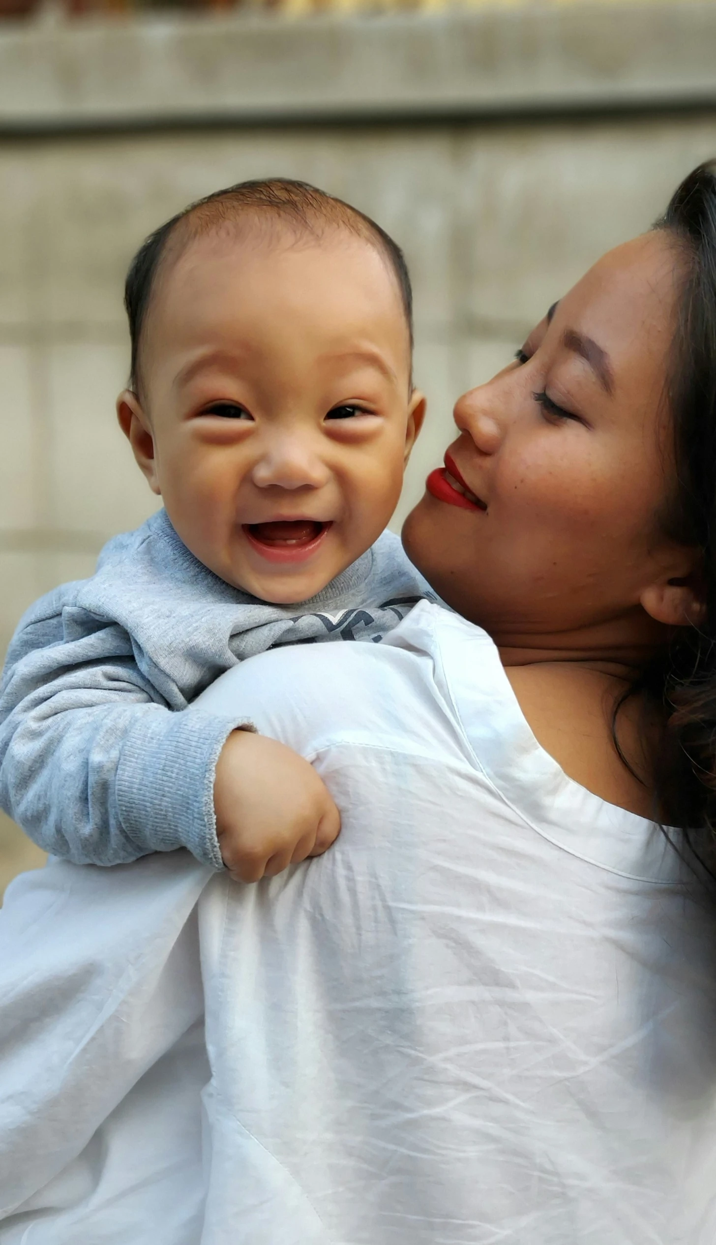 a woman holding her infant who is smiling and looking at the camera