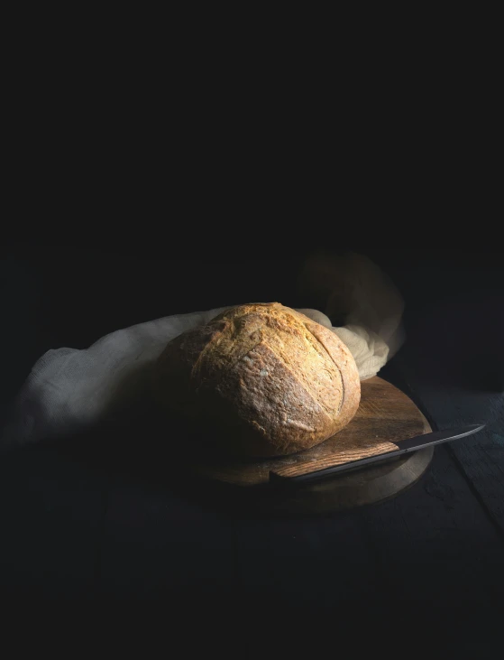 a loaf of bread sitting on top of a  board next to a knife