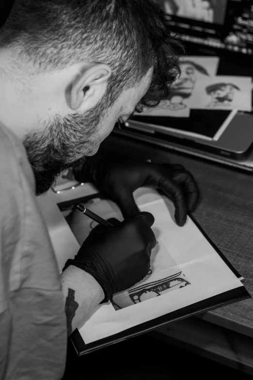 black and white image of man writing in notebook