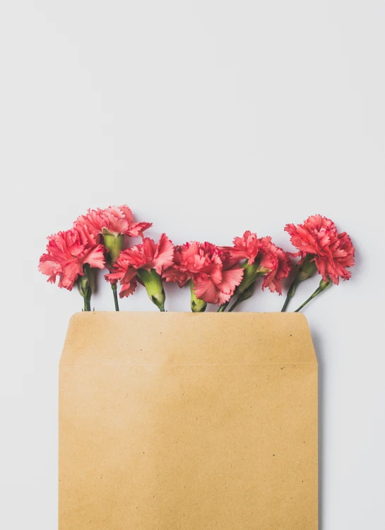 there are flowers in a paper vase on the table