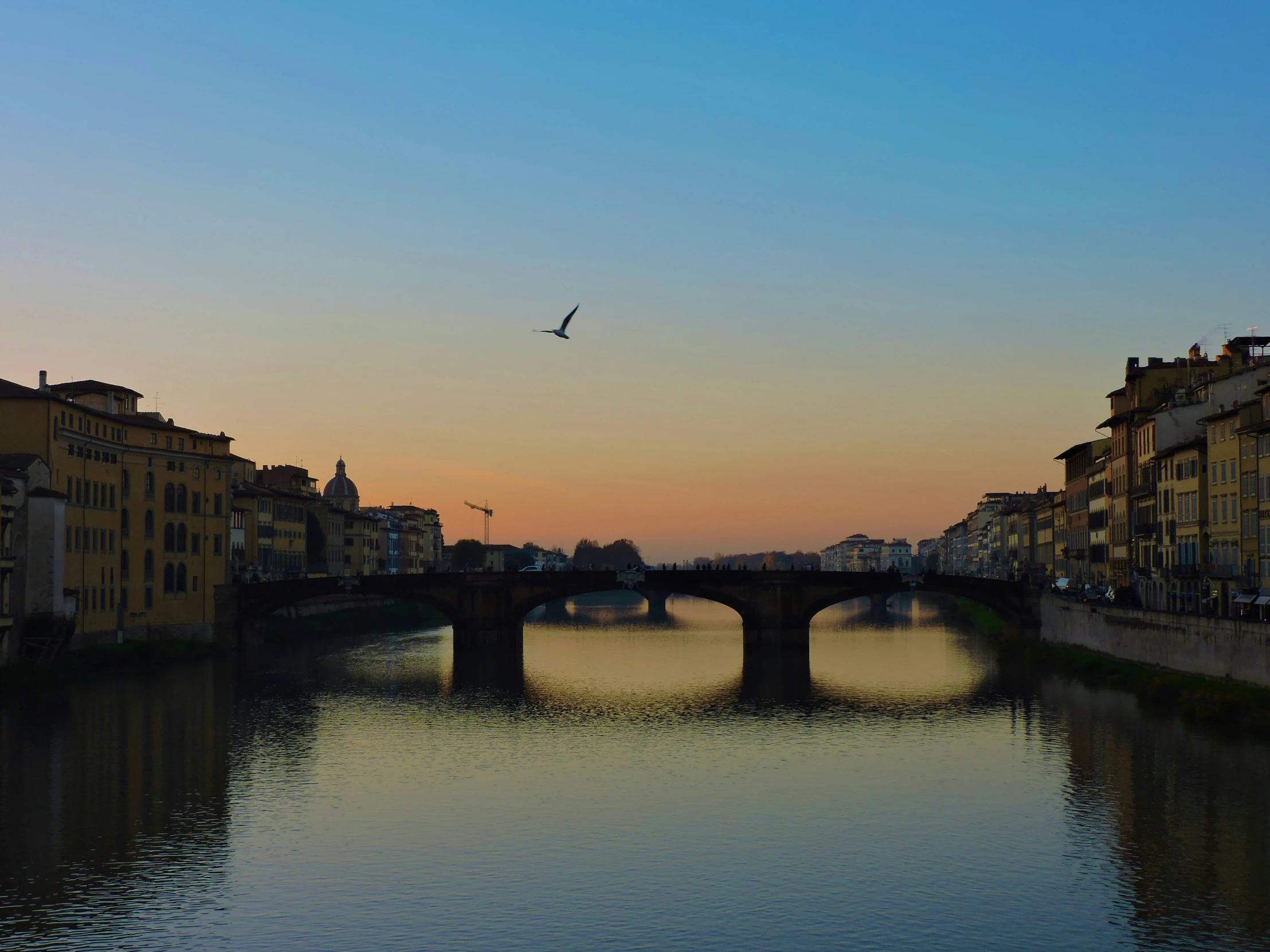 a view of an old bridge and some buildings at sunset