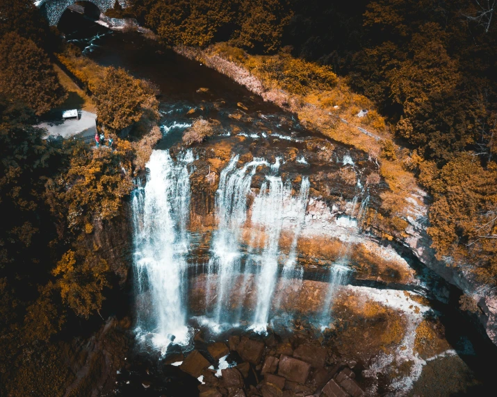 a waterfall in the woods with leaves on it