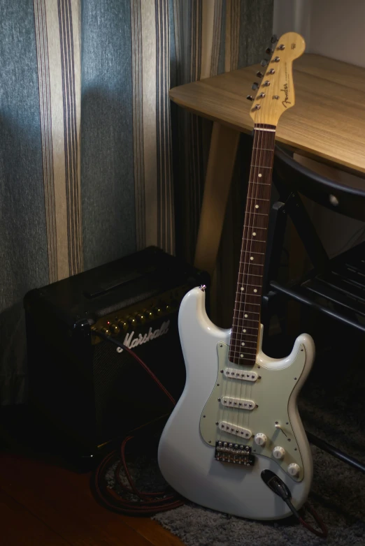 a white electric guitar in front of a speaker