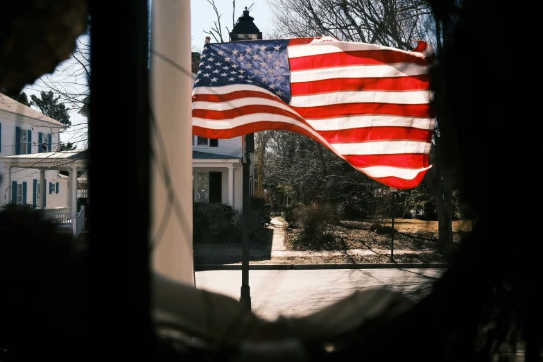 a large american flag is seen through a window