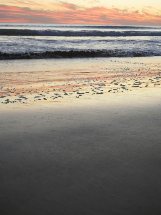 there is a man walking along the beach with a surf board