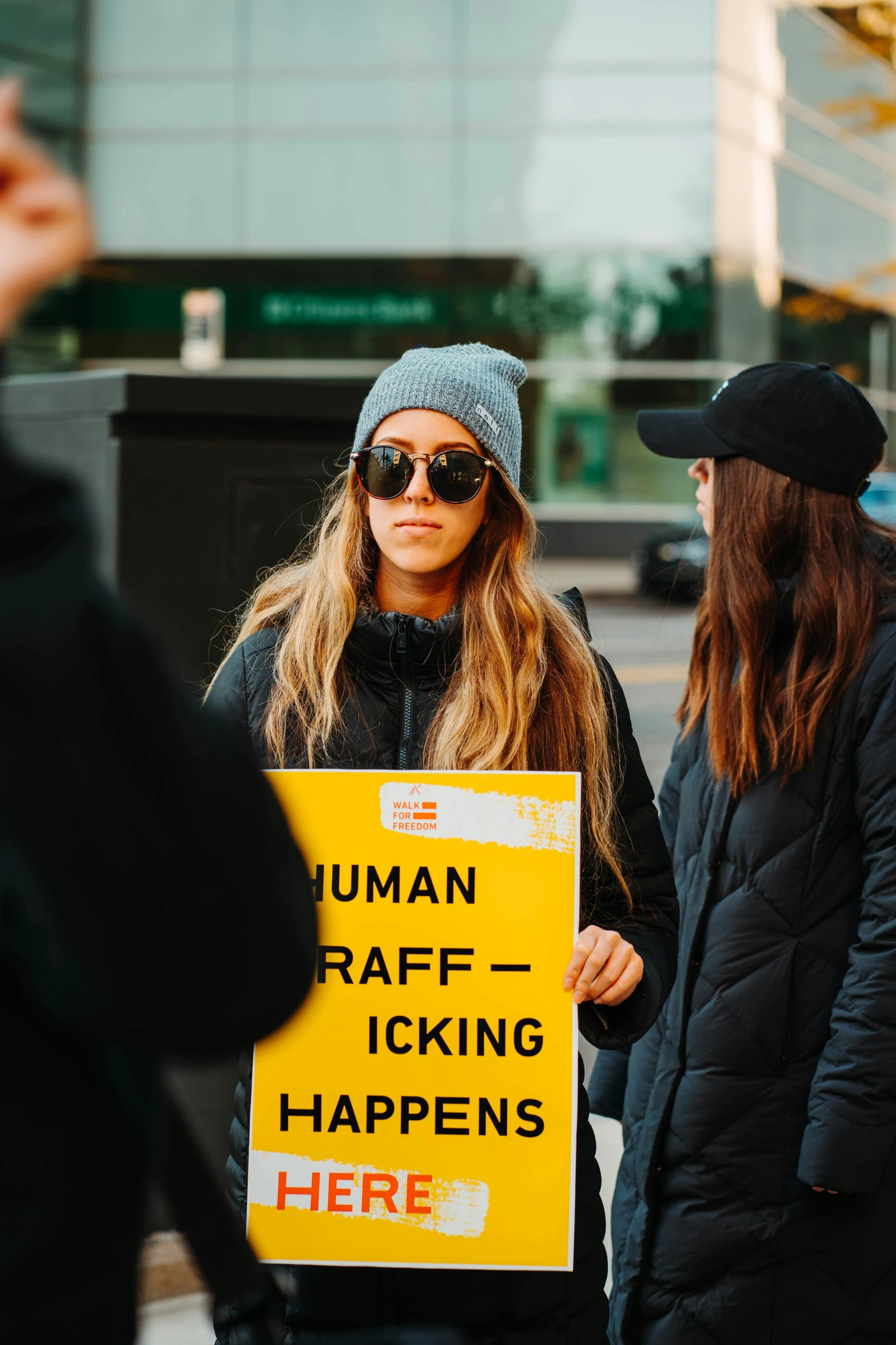 a woman holding a yellow sign standing next to a woman in black