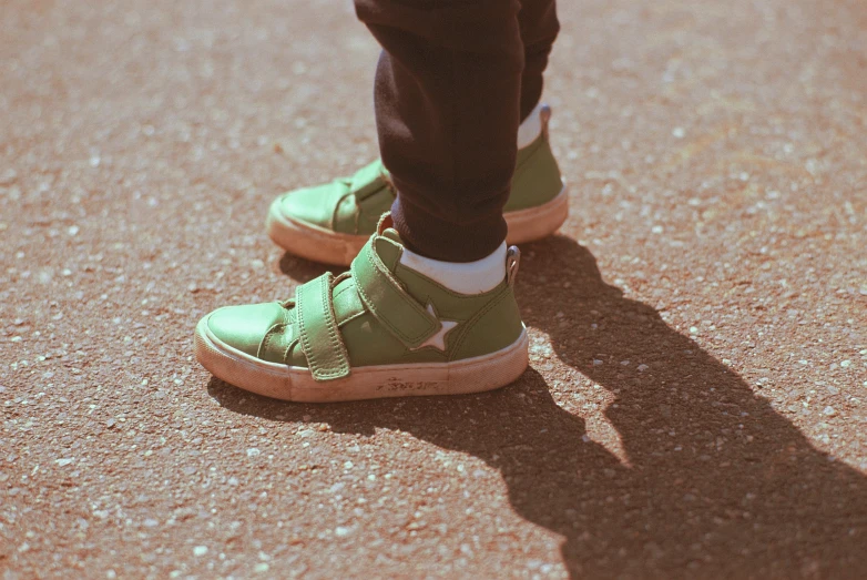 a person standing up wearing green shoes with one white star on it