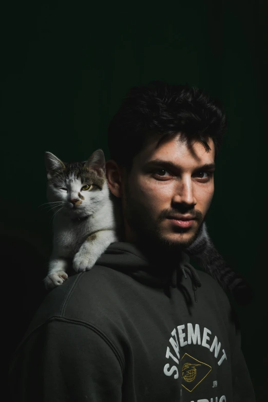 a man in a black hoodie is holding a cat