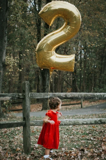 a  is holding up the number two balloon