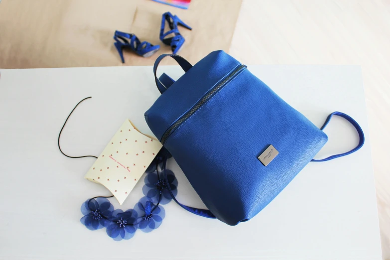 blue purse laying on a table with a tag attached to it