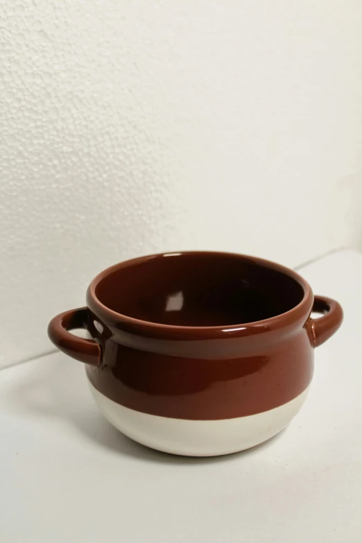 a brown bowl that is on a white surface