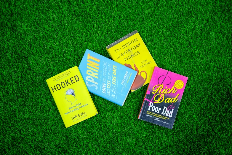three books sitting on top of grass