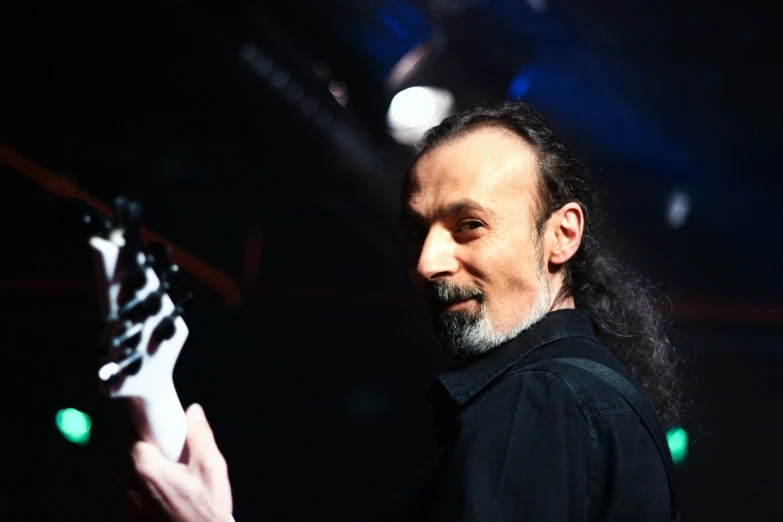 a man with long hair holding an electric guitar