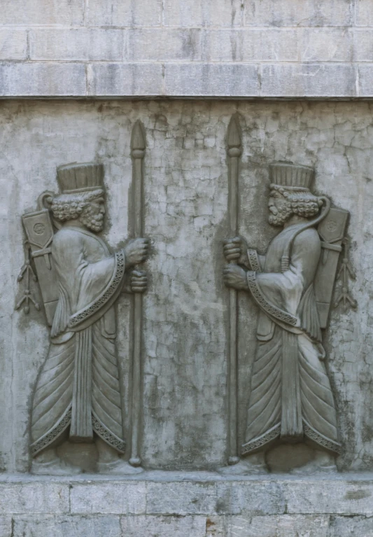 two decorative carved stone panels are attached to the side of a building