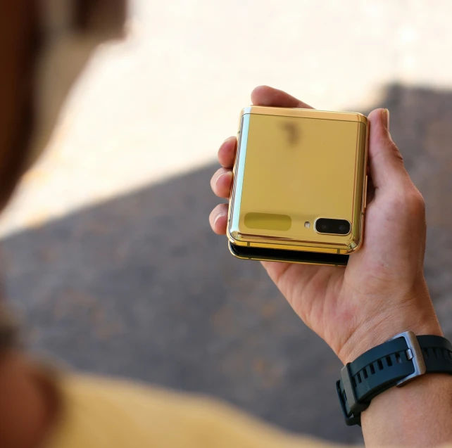 a person holding a phone that is gold