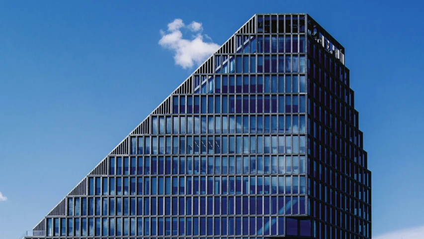 an angled glass building, with blue sky above